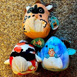 Three small squishmallows: koi fish, painted dog, pizza Dino.